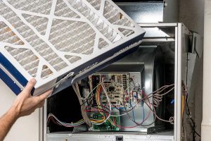 Technician replacing air filter in a furnace unit