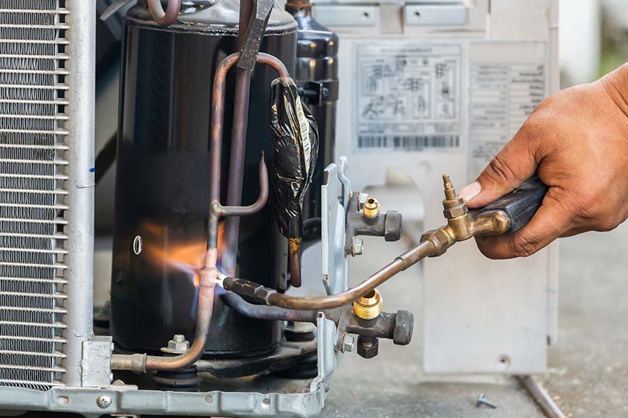 AC technician brazing pipes